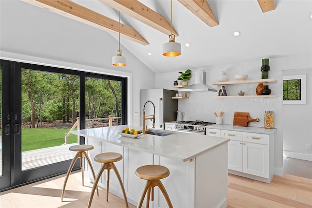 kitchen with wall chimney exhaust hood, stainless steel range with gas stovetop, vaulted ceiling with beams, white cabinets, and tasteful backsplash