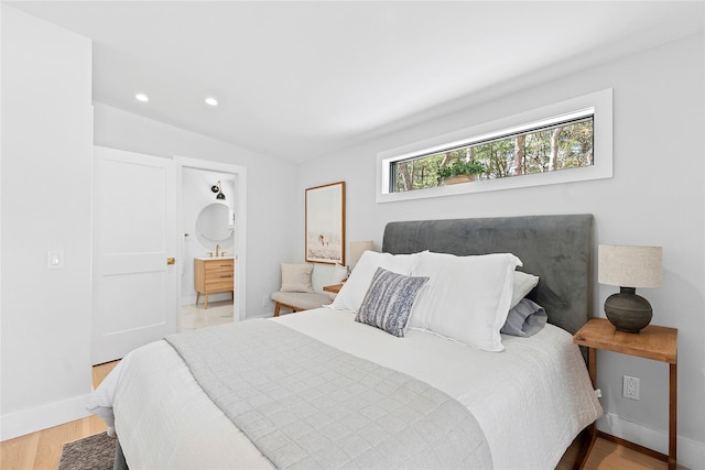 bedroom with connected bathroom, wood finished floors, baseboards, and recessed lighting
