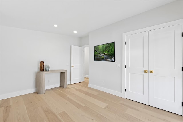 unfurnished bedroom featuring a closet, light wood-style flooring, baseboards, and recessed lighting