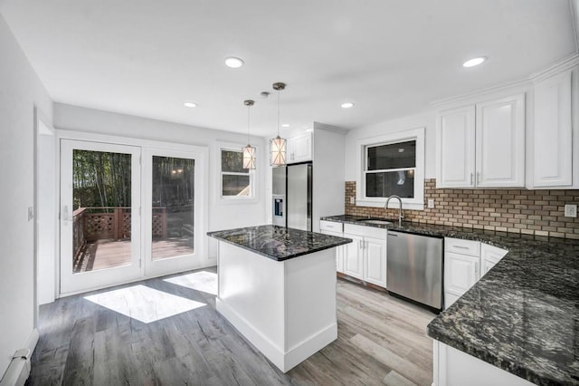 kitchen featuring white cabinetry, tasteful backsplash, a sink, light wood-style flooring, and appliances with stainless steel finishes