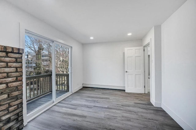 empty room with baseboards, recessed lighting, a baseboard heating unit, and wood finished floors