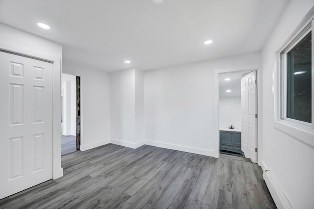 empty room with recessed lighting, baseboards, a baseboard heating unit, and wood finished floors