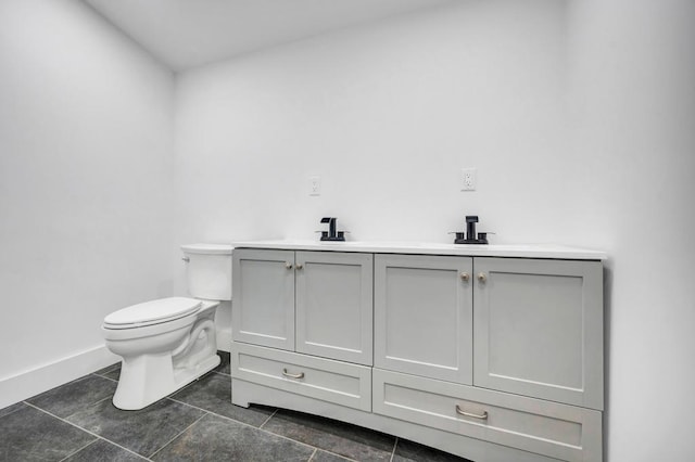 bathroom featuring double vanity, tile patterned flooring, a sink, baseboards, and toilet