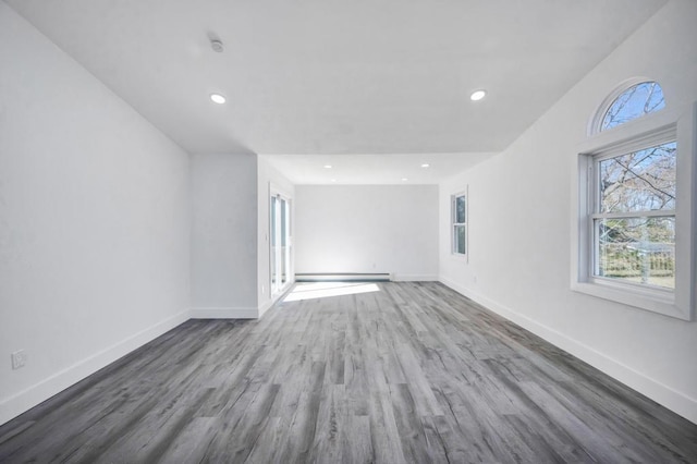 unfurnished living room featuring baseboards, a baseboard radiator, and wood finished floors