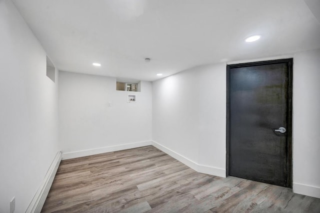 finished basement with baseboards, a baseboard heating unit, recessed lighting, and wood finished floors