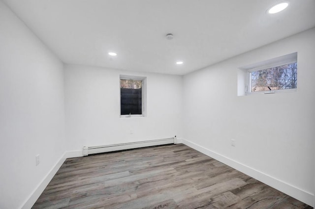 below grade area with recessed lighting, baseboards, wood finished floors, and baseboard heating