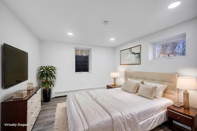 bedroom featuring wood finished floors, recessed lighting, and a baseboard heating unit