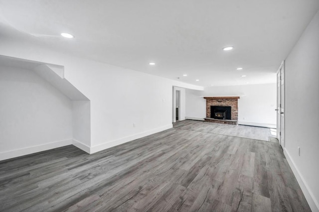 unfurnished living room featuring baseboards, a fireplace, recessed lighting, and wood finished floors