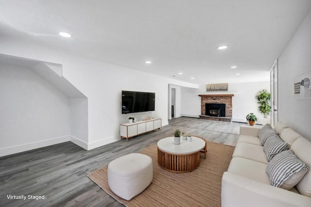 living area with baseboards, a brick fireplace, recessed lighting, and wood finished floors