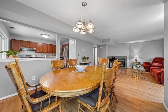 2816 Whispering Hls, Chester, NY 10918 - dining area with light wood-type flooring, a fireplace, a chandelier, and baseboards