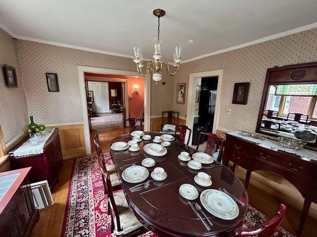 43-51 166th St, Flushing, NY 11358 - dining area featuring crown molding, wood finished floors, a wainscoted wall, a notable chandelier, and wallpapered walls