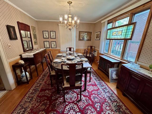 43-51 166th St, Flushing, NY 11358 - dining space featuring ornamental molding, light wood-style flooring, a wainscoted wall, and a notable chandelier