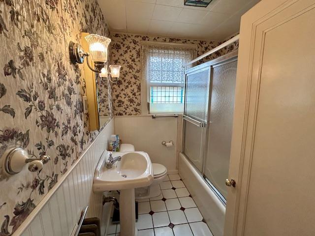 43-51 166th St, Flushing, NY 11358 - bathroom with wainscoting, a sink, toilet, wallpapered walls, and combined bath / shower with glass door