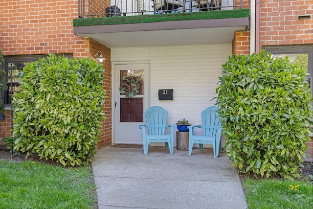 property entrance featuring brick siding and a balcony