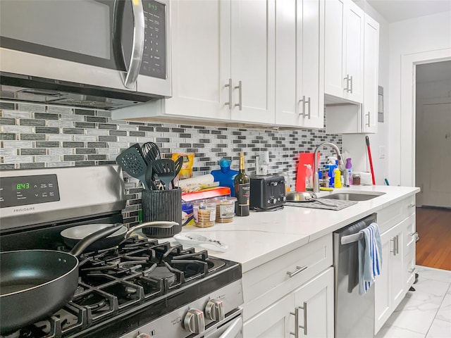 kitchen featuring a sink, appliances with stainless steel finishes, white cabinets, and tasteful backsplash