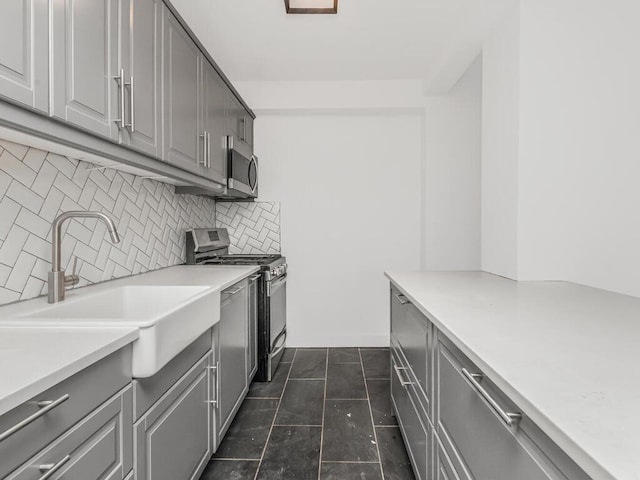 kitchen featuring a sink, appliances with stainless steel finishes, gray cabinetry, and tasteful backsplash