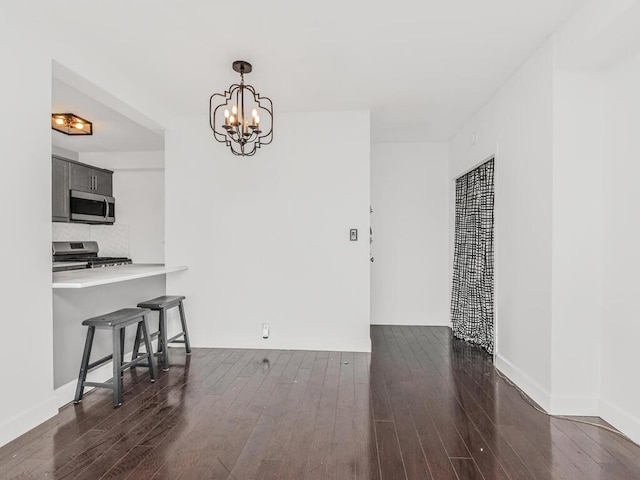 dining space featuring an inviting chandelier, dark wood finished floors, and baseboards