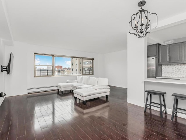 living room featuring dark wood finished floors, a baseboard heating unit, and a chandelier