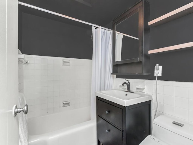 full bathroom with vanity, shower / bath combo with shower curtain, toilet, and tile walls