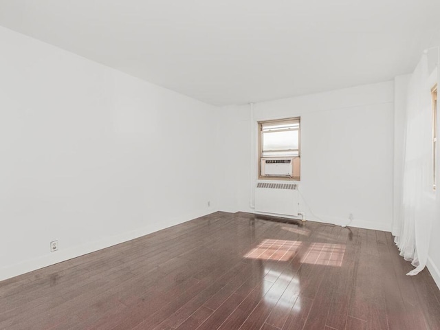 unfurnished room with radiator, wood finished floors, and cooling unit