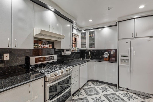 kitchen with under cabinet range hood, white appliances, white cabinets, and tasteful backsplash