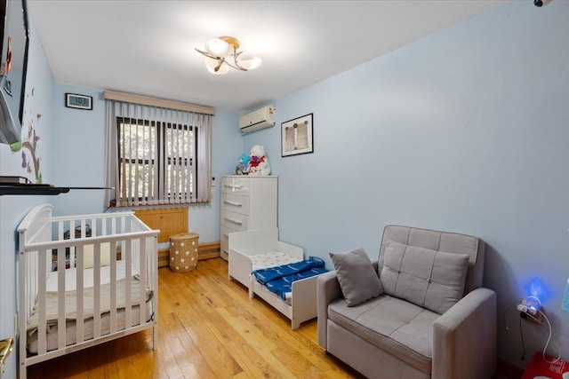 bedroom featuring light wood finished floors and a wall mounted AC