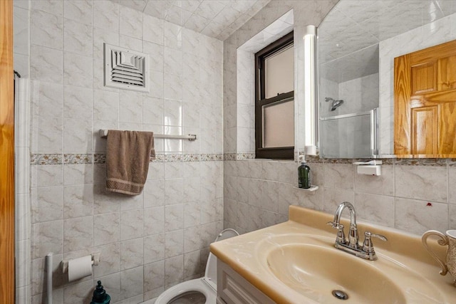 bathroom featuring vanity, tile walls, toilet, and a tile shower