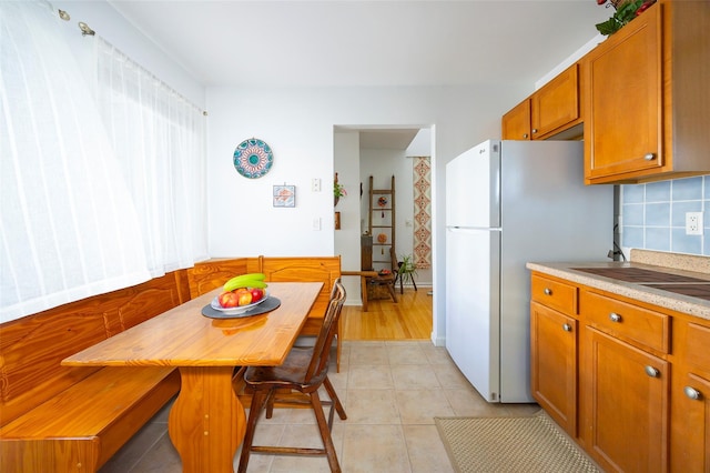 412 Crystal Hill Ln, Poughkeepsie, NY 12603 - kitchen with brown cabinetry, backsplash, light tile patterned floors, freestanding refrigerator, and breakfast area