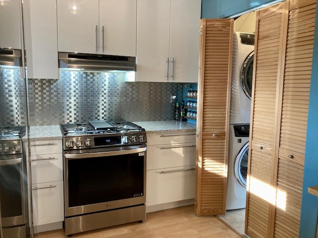 kitchen with stacked washer and clothes dryer, decorative backsplash, under cabinet range hood, and gas stove