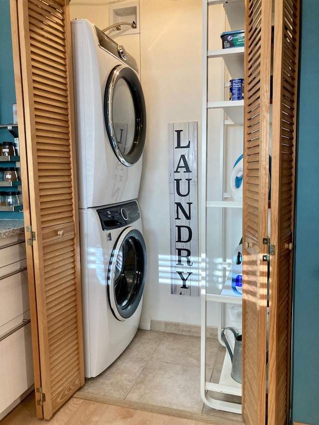 laundry area featuring stacked washing maching and dryer and tile patterned floors