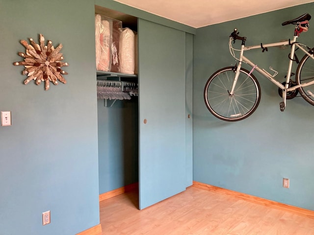 unfurnished bedroom with baseboards, a closet, and wood finished floors