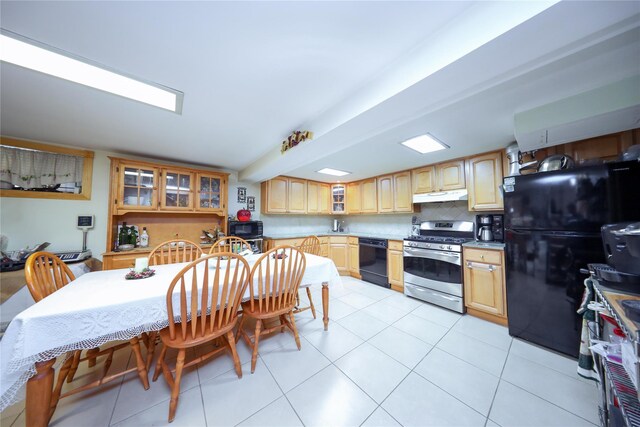 1464 W 5th St, Brooklyn, NY 11204 - kitchen with black appliances, under cabinet range hood, glass insert cabinets, tasteful backsplash, and light brown cabinetry