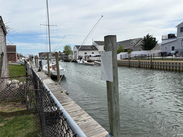 view of dock featuring a water view, fence, and a residential view
