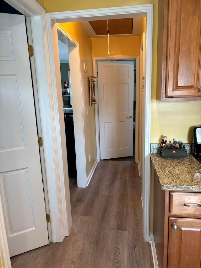 hall featuring baseboards, attic access, and dark wood finished floors