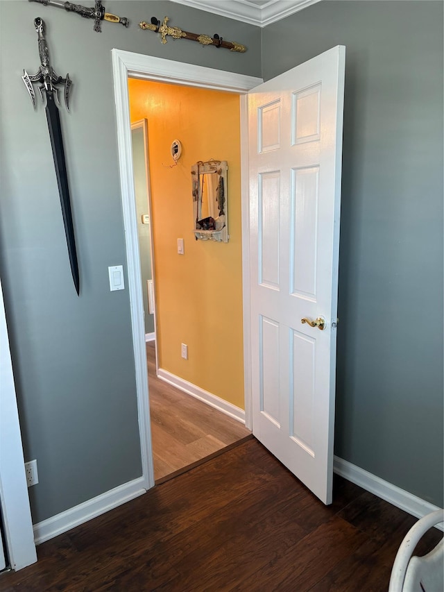 hall featuring baseboards, ornamental molding, and wood finished floors