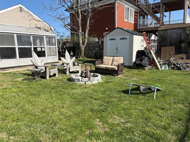 view of yard featuring a storage shed, an outdoor structure, a sunroom, and an outdoor fire pit