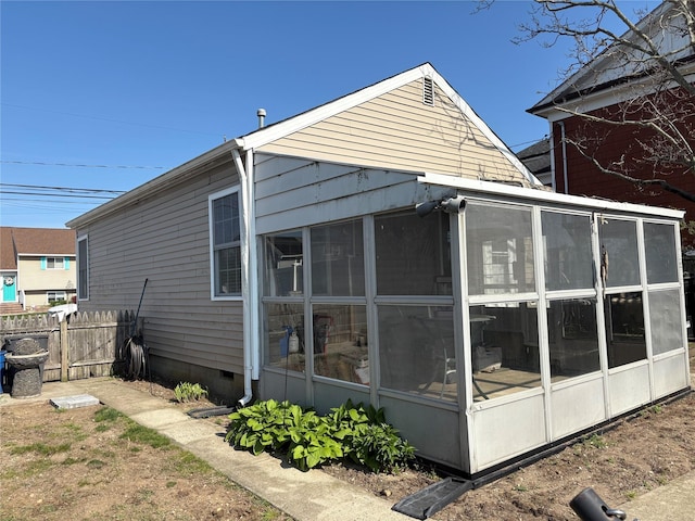 rear view of property featuring fence, a sunroom, and crawl space