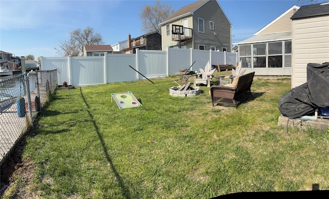 view of yard featuring a fenced backyard, a sunroom, and an outdoor fire pit