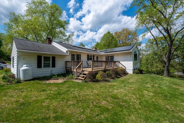 11 Mcintosh Dr, Poughkeepsie, NY 12603 - back of property with a chimney, a yard, a wooden deck, and roof mounted solar panels