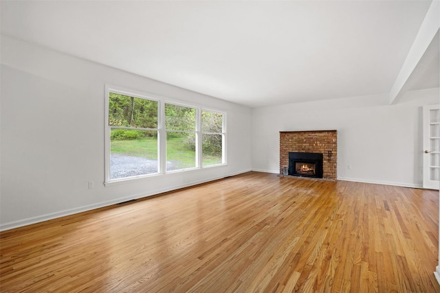 unfurnished living room featuring light wood-type flooring, baseboards, and a brick fireplace