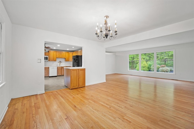unfurnished living room with light wood-type flooring, a chandelier, baseboards, recessed lighting, and a sink