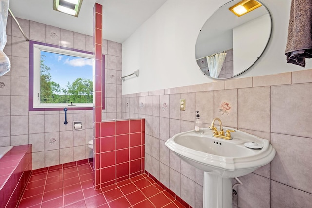 full bath with tile walls, tile patterned flooring, and a sink