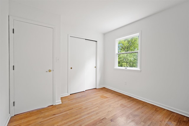 unfurnished bedroom with light wood-type flooring, baseboards, and a closet