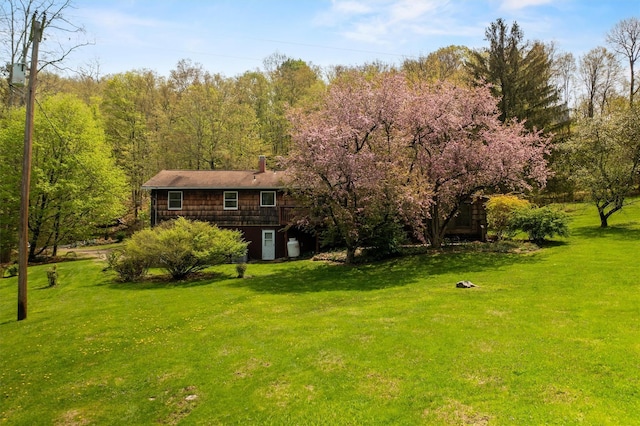 view of green lawn featuring a forest view
