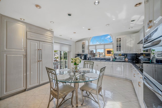 3452 Ocean Ave, Oceanside, NY 11572 - kitchen featuring dark countertops, glass insert cabinets, light tile patterned floors, tasteful backsplash, and double oven