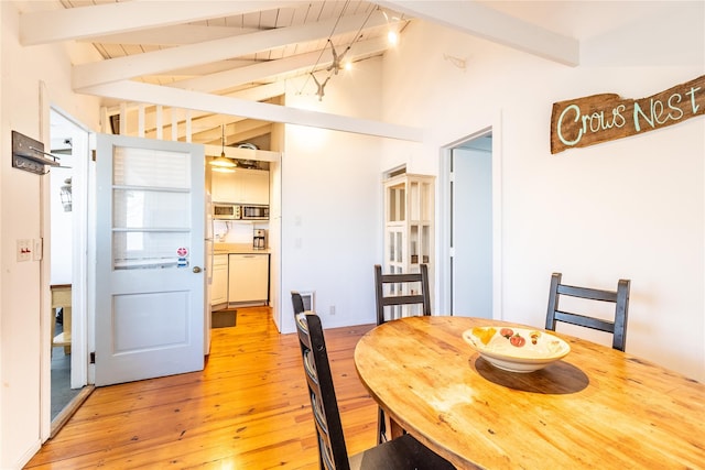 dining room featuring lofted ceiling with beams and light wood-type flooring