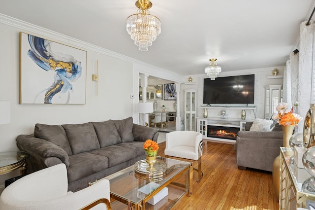 living room featuring ornamental molding, light wood-type flooring, and a chandelier