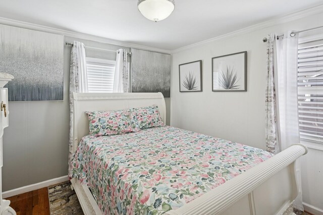 bedroom featuring baseboards, ornamental molding, and wood finished floors
