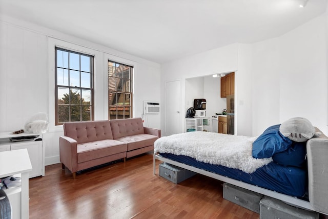 bedroom featuring a wall unit AC and wood finished floors