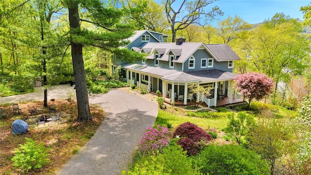 8 Manitou Rdg, Garrison, NY 10524 - view of front of home featuring covered porch, a chimney, an outdoor fire pit, and aphalt driveway